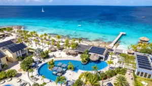 Luchtfoto van een resort aan zee op de ABC-eilanden met zwembad, palmbomen en turquoise water