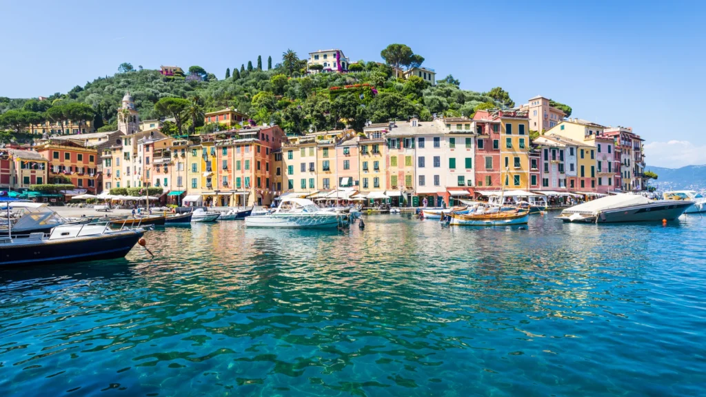 Uitzicht op een kleurrijk kustdorp in Italië met boten in de haven en helderblauw water